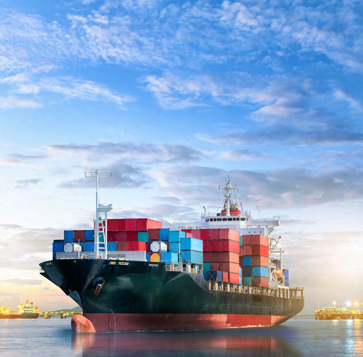 Container vessel departing port at sunset